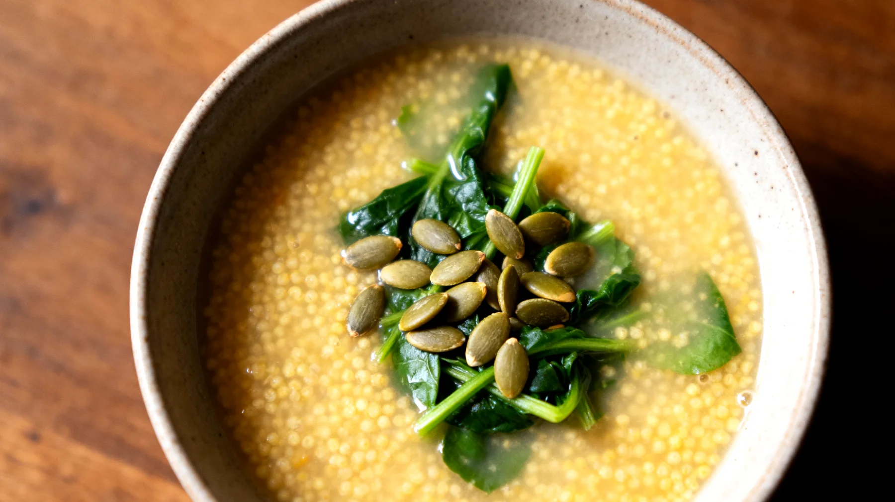 Zuppa di miglio con verdure a foglia verde e semi di zucca"